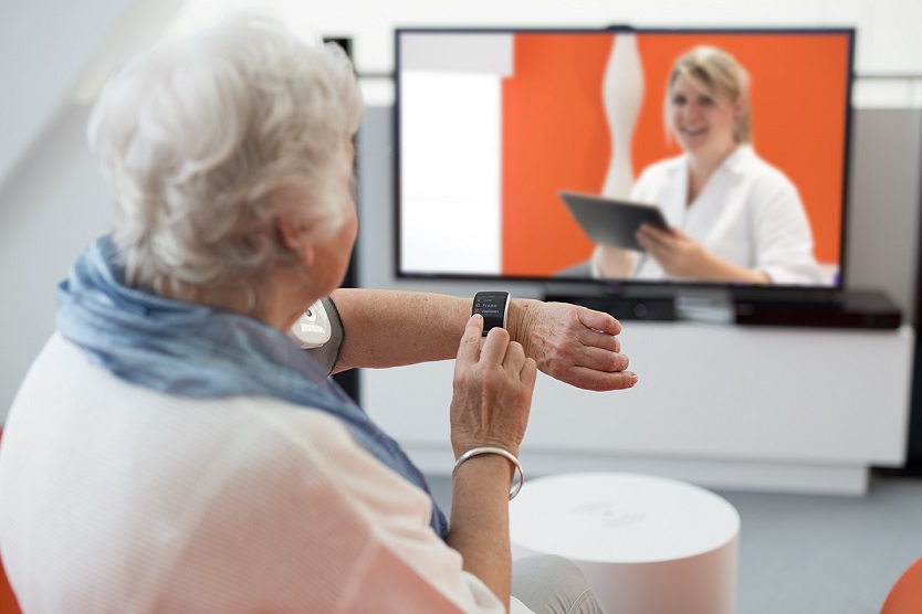 Ältere Frau sitzt vor Bildschirm und kommuniziert mit dem Arzt