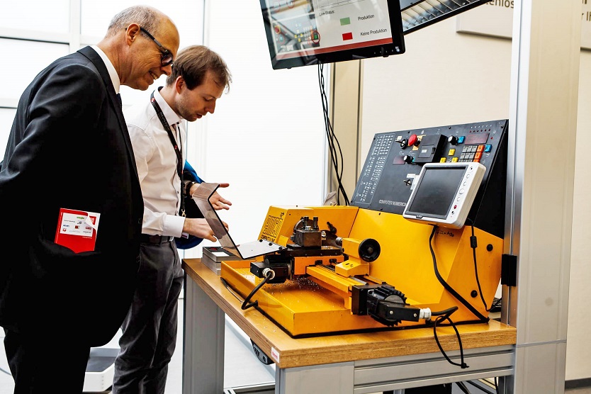Bild zeigt zwei Männer vor einer digital arbeitenden Maschine